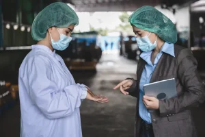 Auditora evaluando a una operaria para verificar controles y medidas preventivas establecidas en la matriz de riesgos BRCGS.