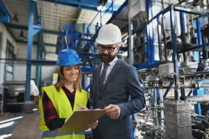 Auditor revisando un informe con una trabajadora durante una auditoría SMETA para evaluar riesgos sociales y condiciones laborales en una planta industrial
