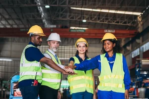 Un grupo de personas del equipo de responsabilidad social uniendo sus manos en el centro, simbolizando el trabajo en equipo y el cumplimiento de los estándares laborales de la OIT.