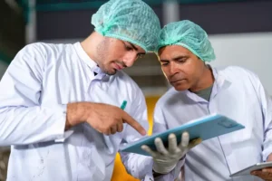 Auditor BRCGS capacitando a un colaborador sobre acciones correctivas y gestión de riesgos durante una auditoría de inocuidad alimentaria.