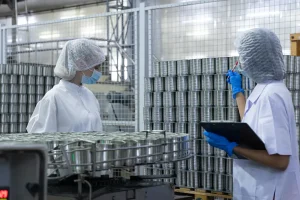 Dos profesionales del área de calidad inspeccionando productos para verificar el cumplimiento de los Puntos Críticos de Control (PCC) en un sistema HACCP.